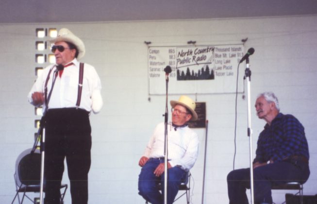 Clarence Richards tells a story at an Adirondack Liars Club performance. Award recipient Bill Smith is also seated on the right.