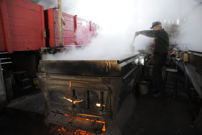 Working with the evaporator in the boiling shed, 2010. Some of the equipment the Yanceys use dates to the first half of the 20th century, and their 1920s-era evaporator is fueled by wood cut on their woodlot. 