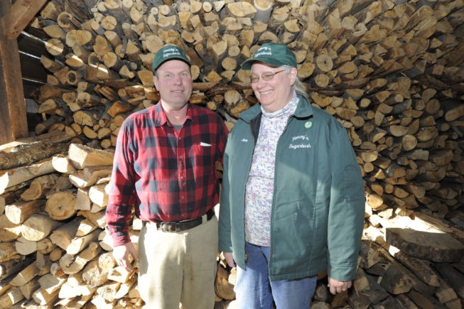 Haskell and Jane Yancey stand by the wood they'll use to fuel the operation's 1920s evaporator, 2010.
