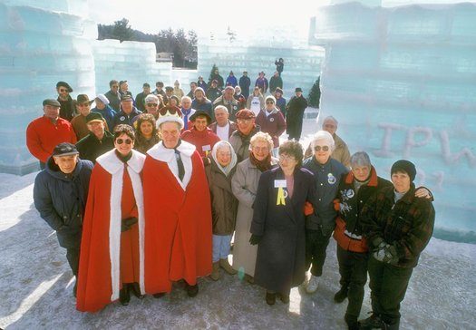 Saranac Lake Winter Carnival royalty, participants, and visitors, 1997. The written IPW 101 visible on the ice wall behind them stands for International Palace Workers (Union) 101. There are different stories about the origin of this being written in slush on the ice palace walls each year, including one that says it was created as a joke in response to tourists repeatedly asking, Why do you do this? 