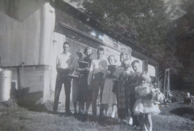 Loretta and siblings line up for school in front of the garage where they lived for nine years, the three youngest girls sharing a bed, while her parents rebuilt after a house fire at her family farm on Kentner Rd. near Constableville. NY. Photographer unknown, 1960. Courtesy of Loretta Lepkowski.